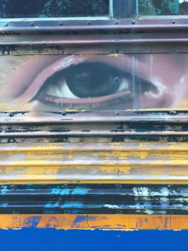 Mural of an eye on the side of a school bus.